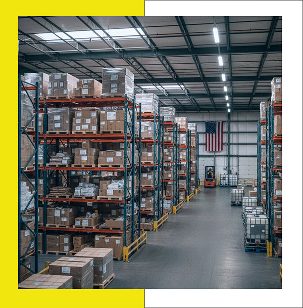 Interior of a warehouse with shelves stocked with boxes and an American flag on the wall.